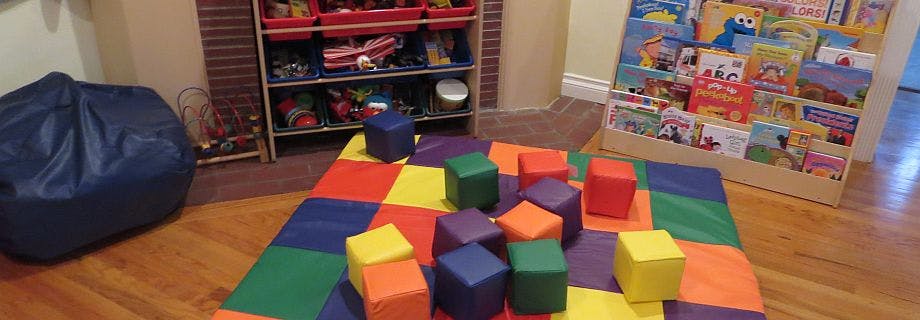 Colorful soft blocks on a play mat in a room with shelves of toys and books