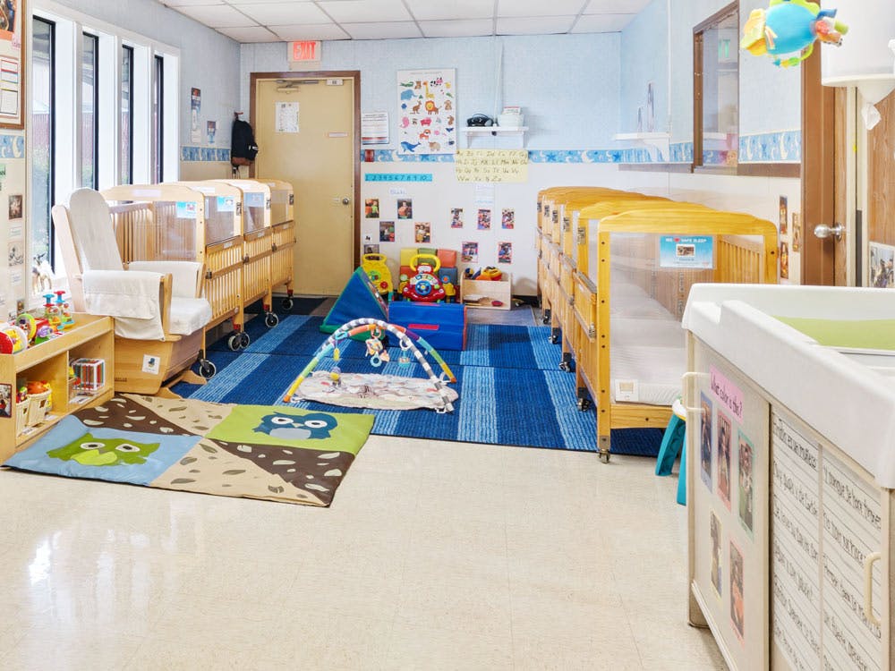Cribs, rocking chair, and play mats in a brightly lit room