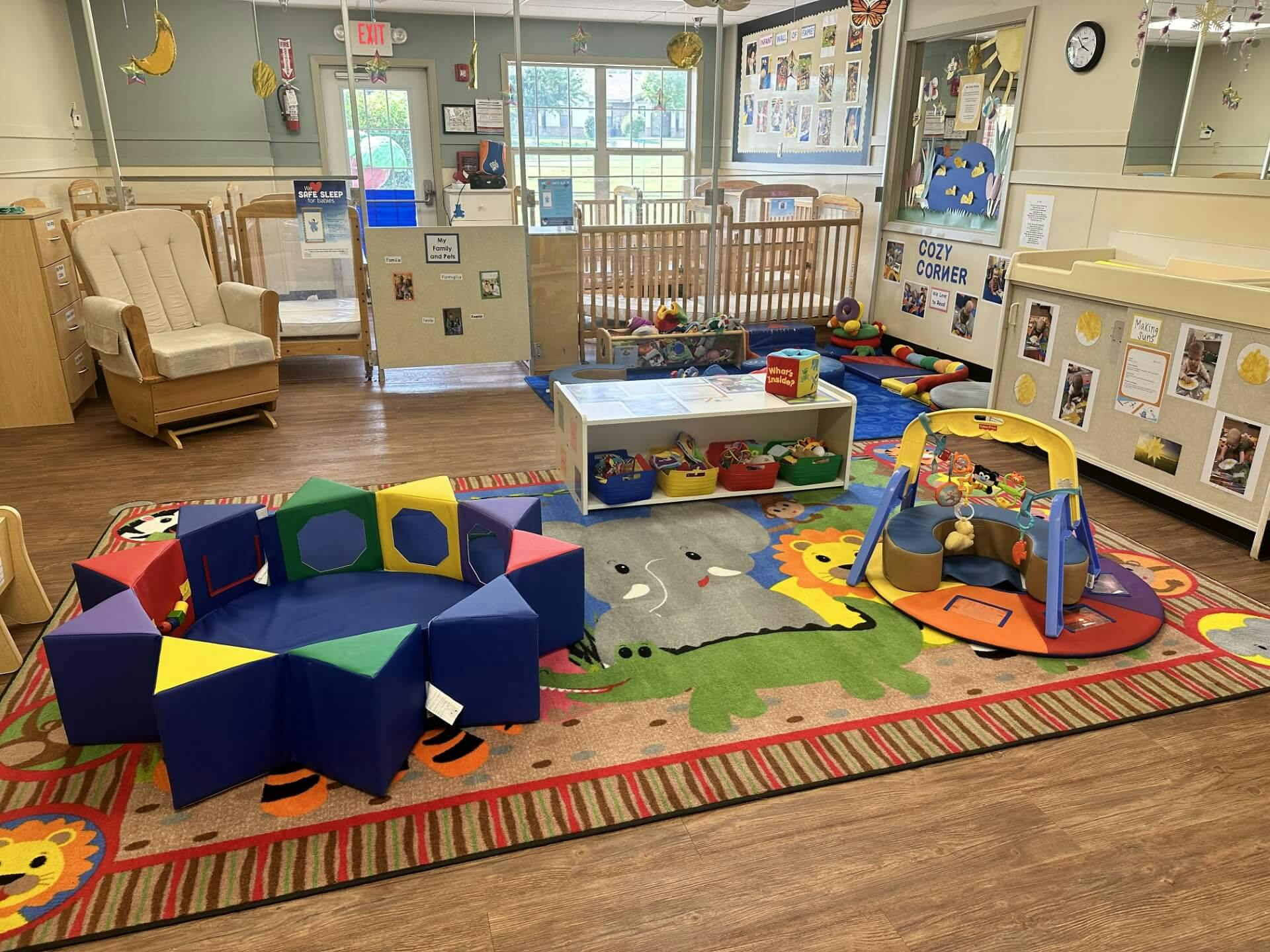 An infant classroom with cribs, rocker, changing table, and play area
