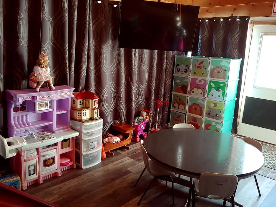 Playroom with toy kitchen, dollhouse, storage unit, and table with chairs