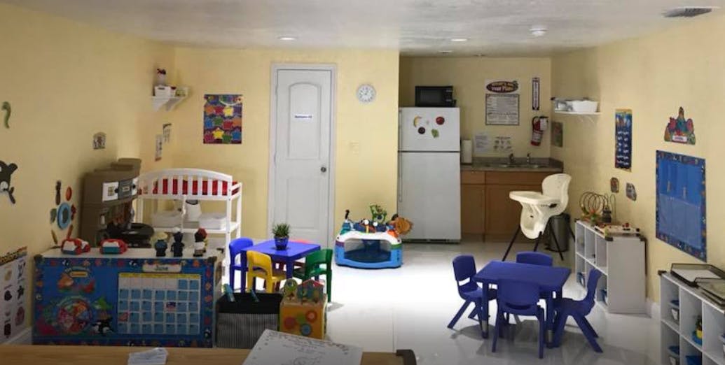 Playroom with small tables and chairs, toy kitchen, and refrigerator