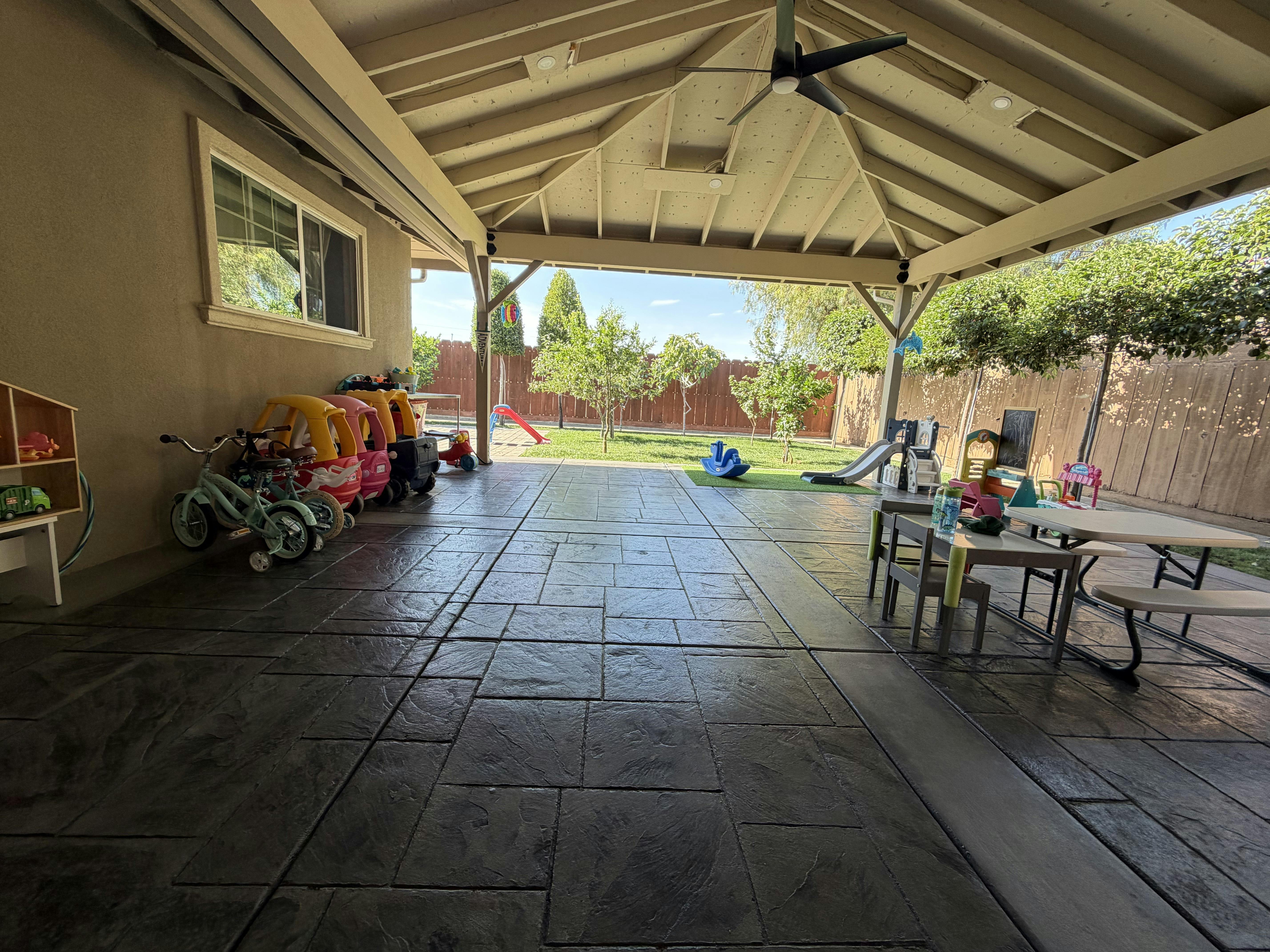 Childrens ride-on toys and outdoor furniture on a covered patio