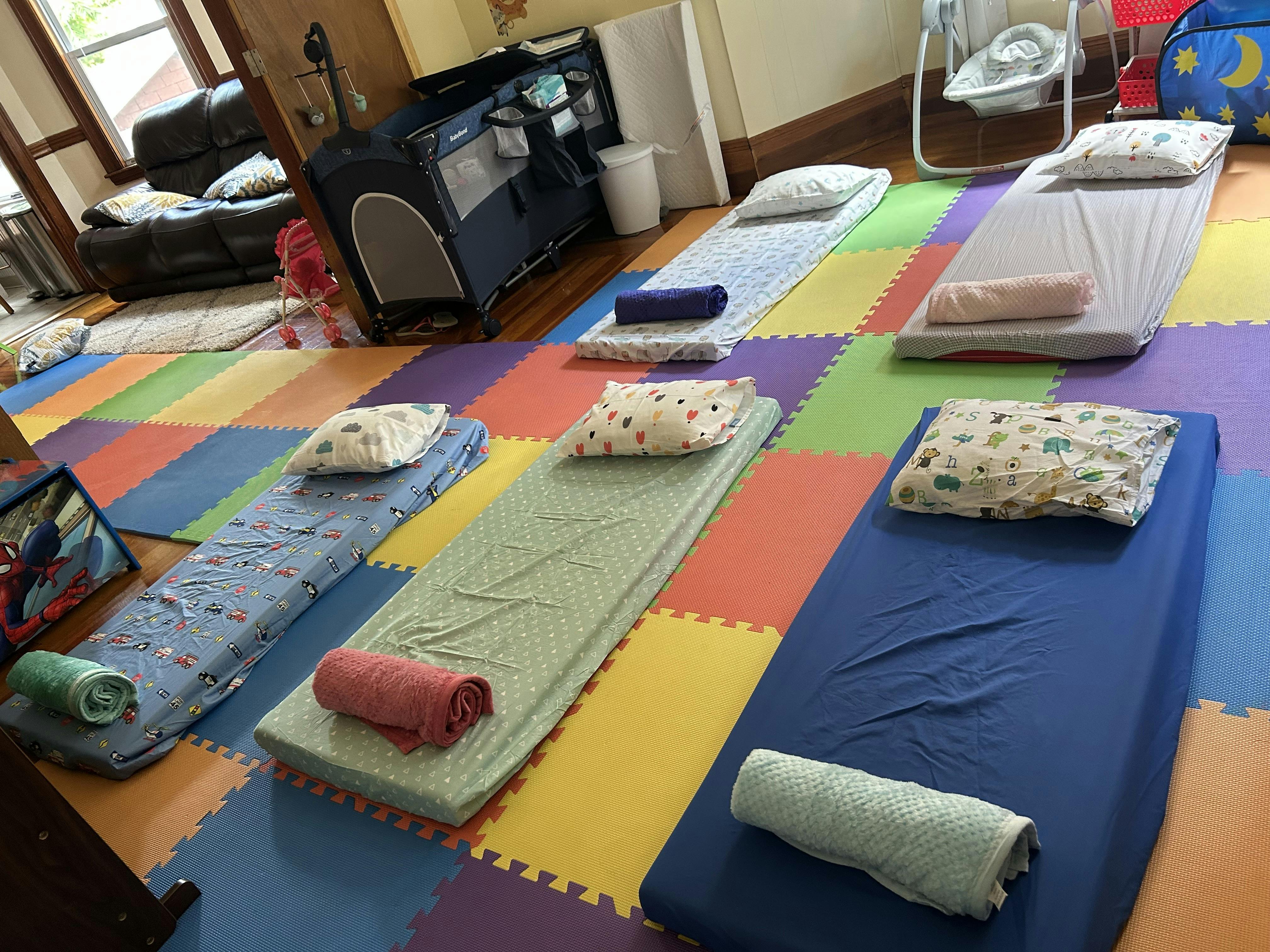 Sleeping mats with pillows and rolled towels on a colorful floor