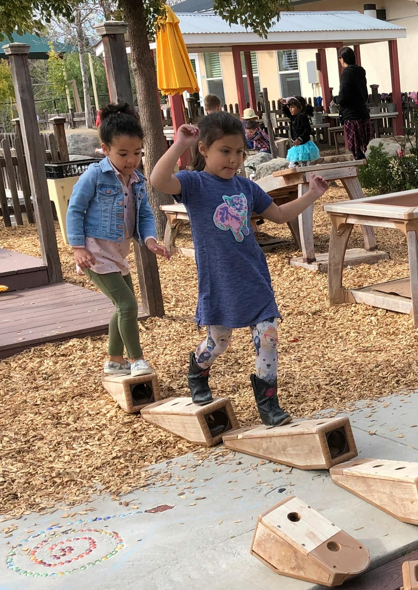 Two children walking on wooden balance beams on a playground