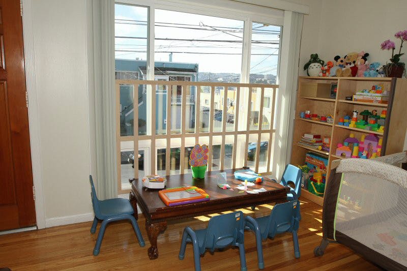 Children's play area with small table and chairs, toys, and a crib