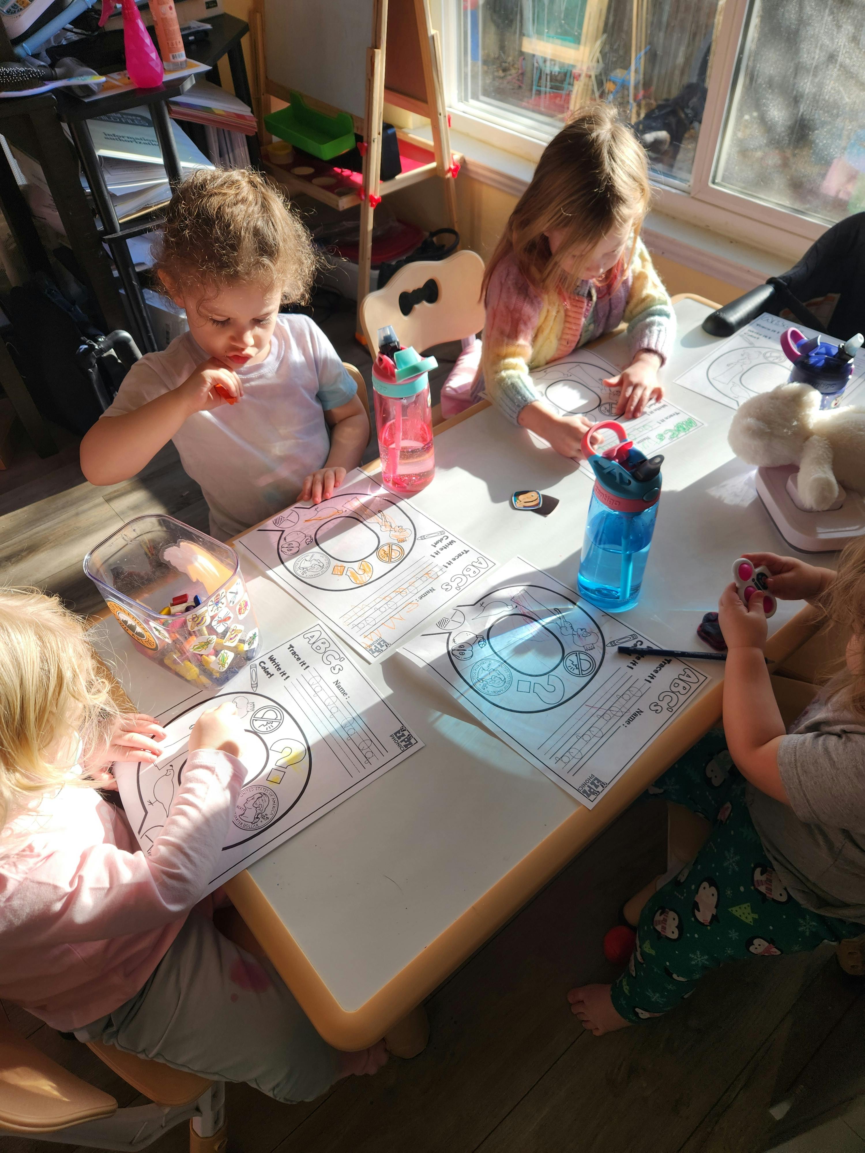 Children sitting at a table with ABC worksheets