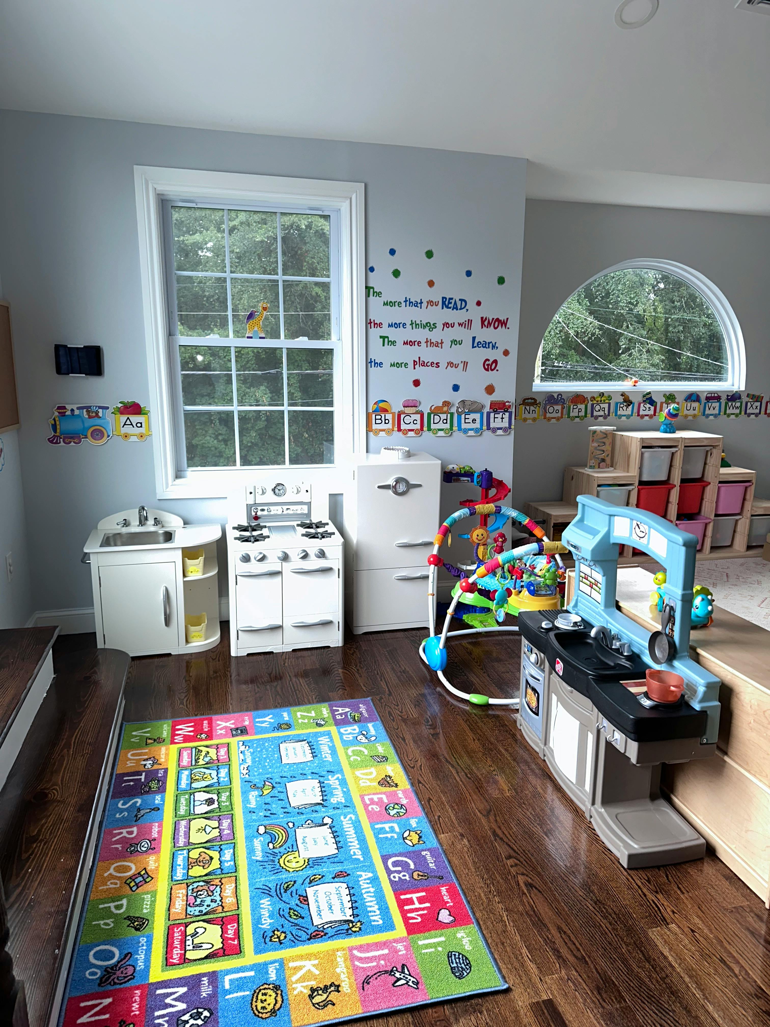 Playroom with toy kitchen, toy appliances, and colorful alphabet rug