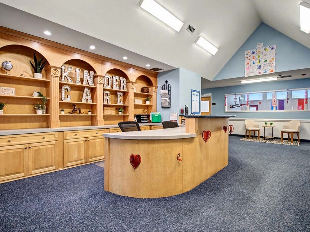 KinderCare sign on a wooden reception desk with shelves in a childcare center