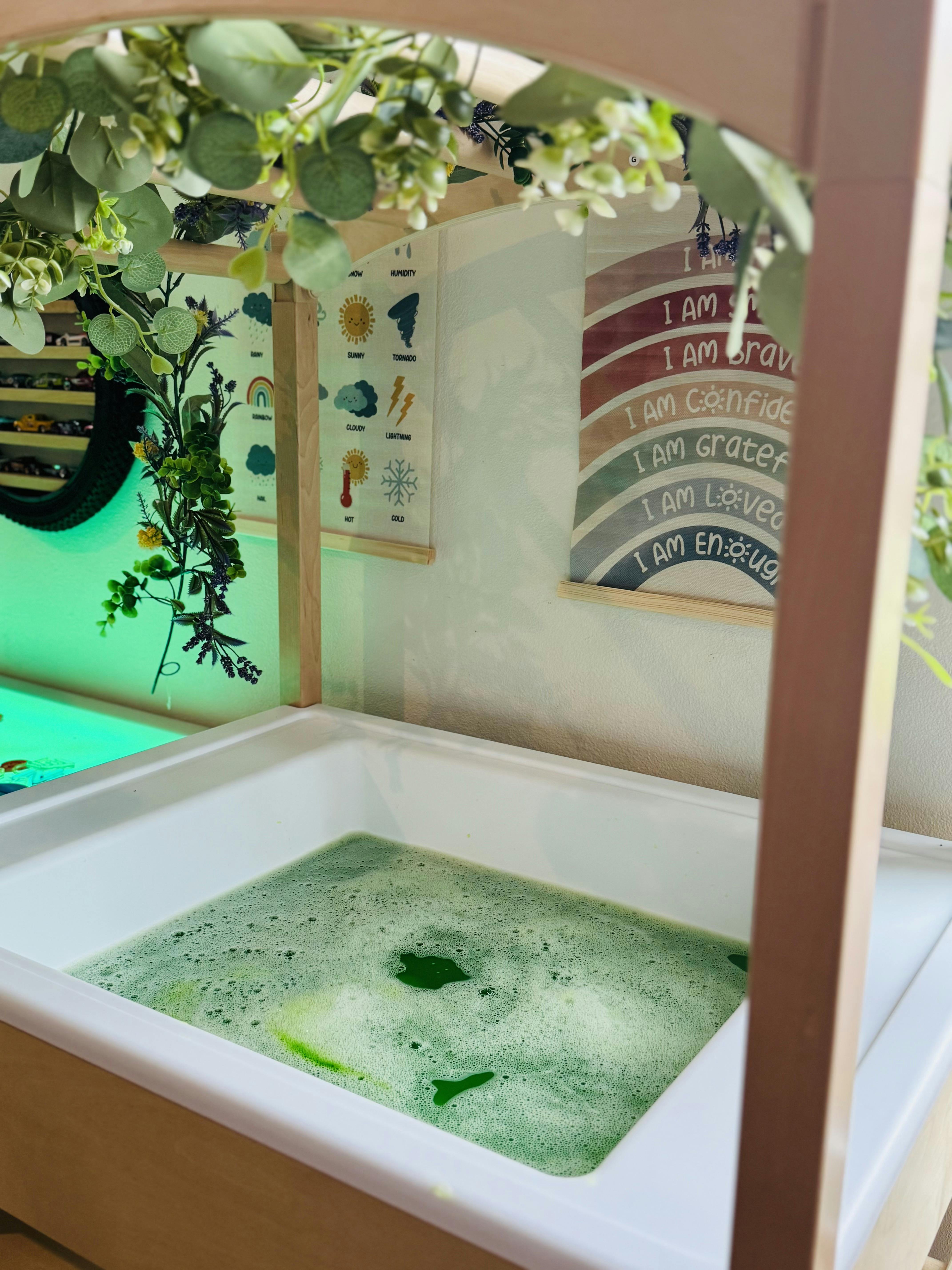 Sensory bin with green foamy liquid