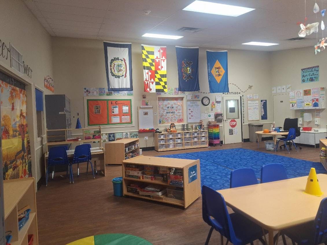 Classroom with tables, chairs, bookshelves, and flags on the wall