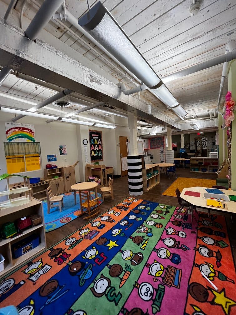 Colorful classroom with child-sized furniture and a rug with cartoon characters