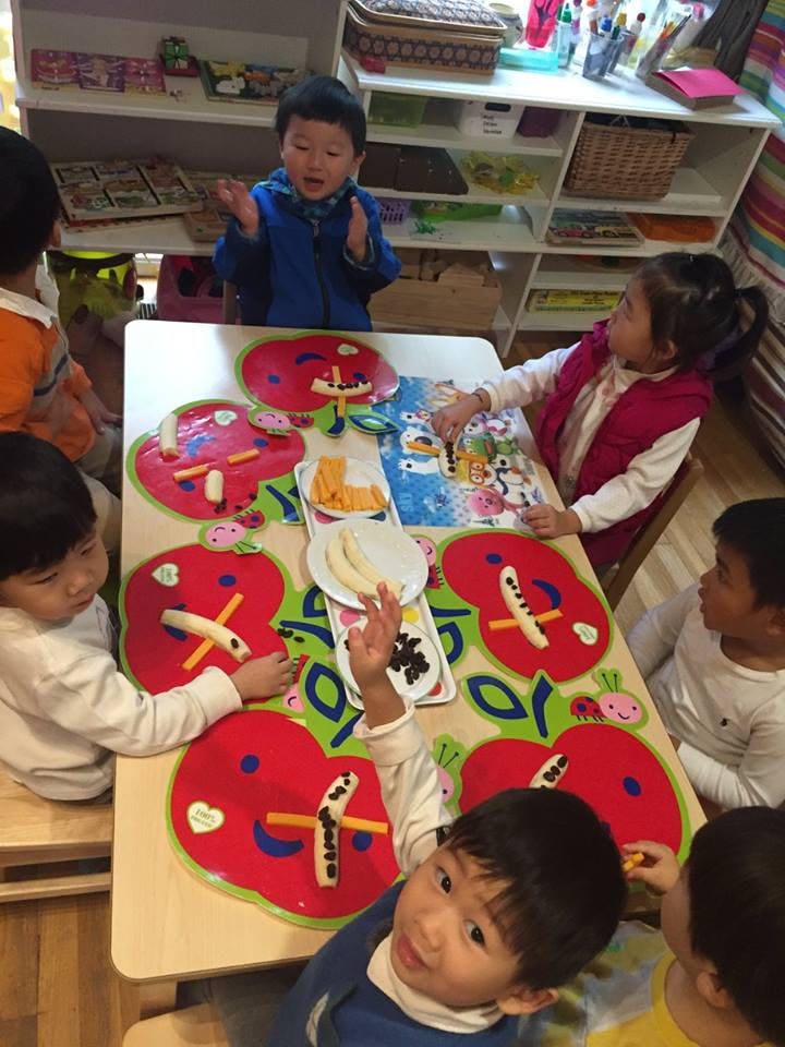 Children at a table with apple-shaped placemats and food items