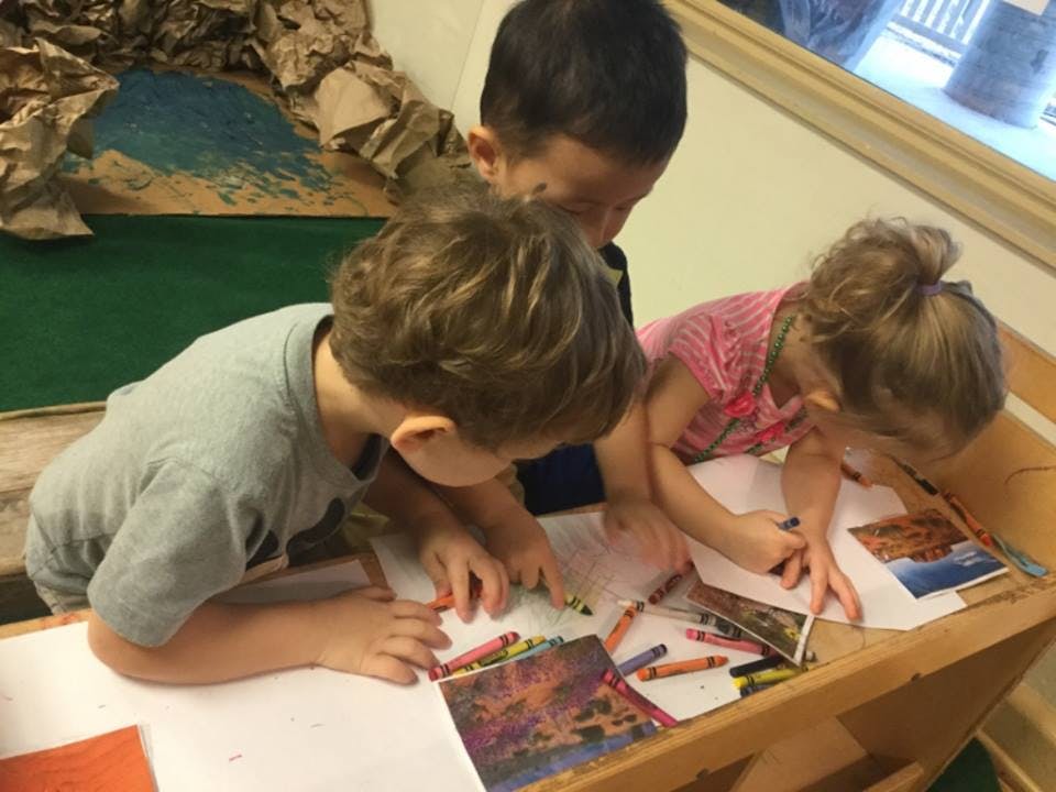 Three children drawing with crayons