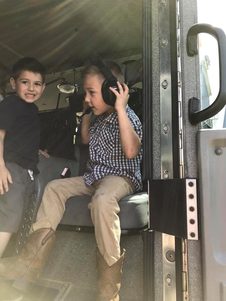 Two children in a vehicle, one wearing headphones