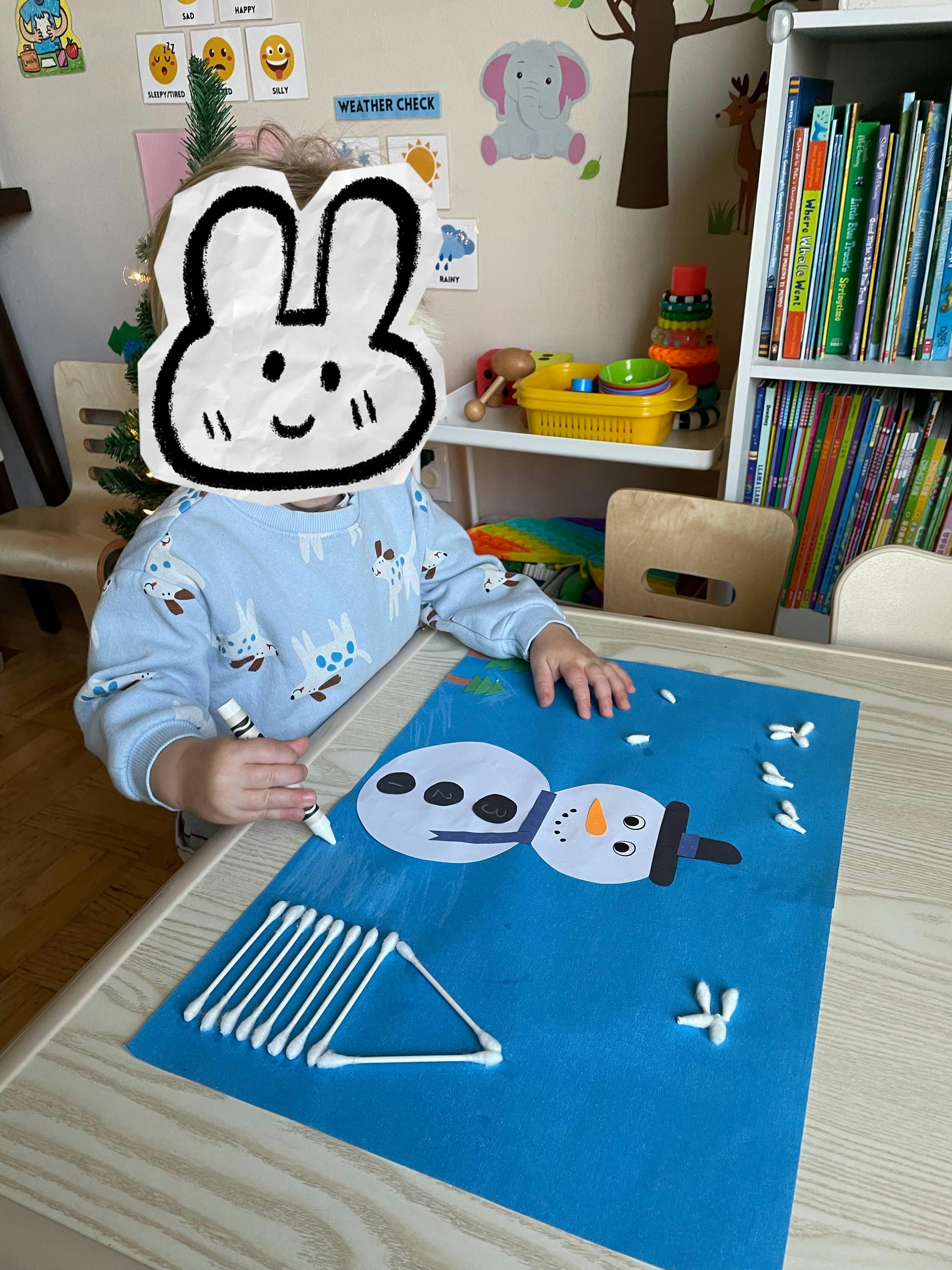 Child making a snowman craft with cotton swabs