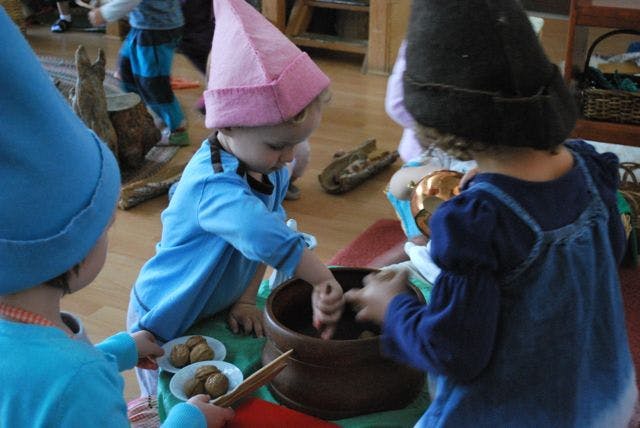 Children in gnome hats playing with bowls and small objects
