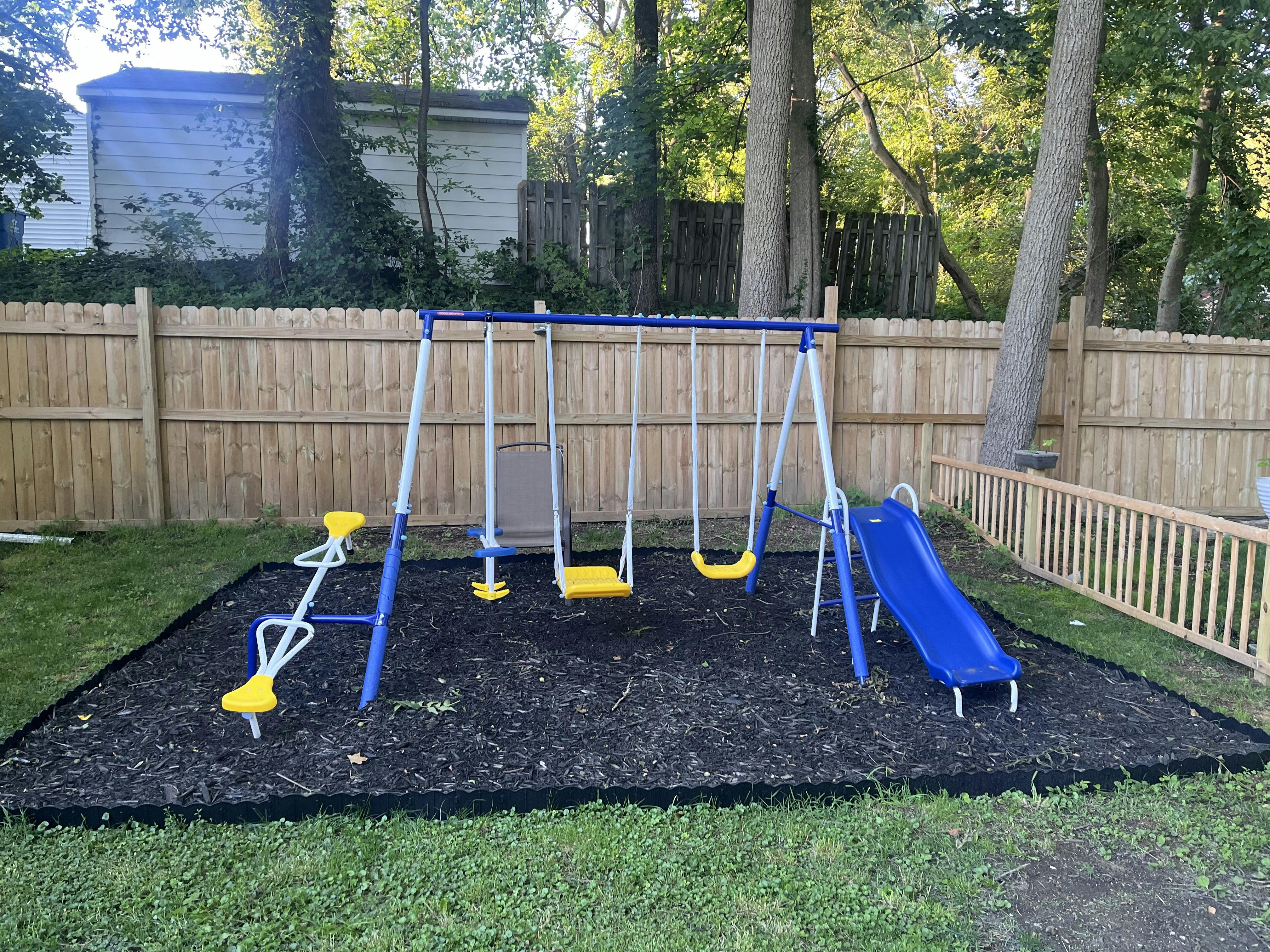 Backyard playground set with swings, a slide, and a teeter-totter