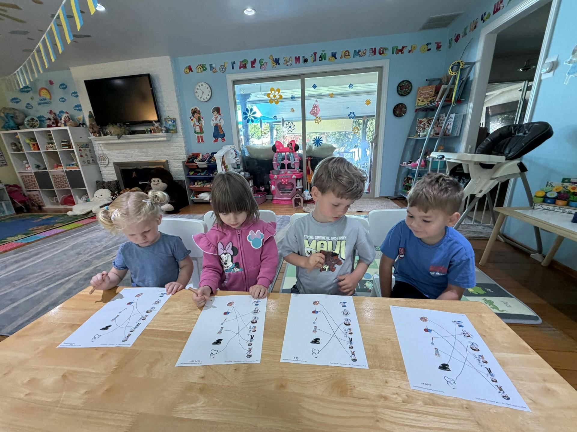 Four children sitting at a table completing a matching worksheet
