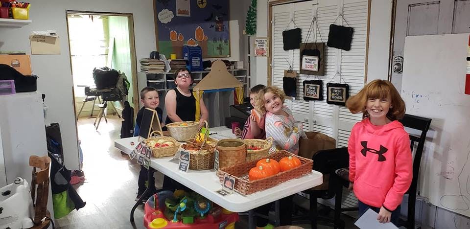Children and adults sitting around a table with baskets