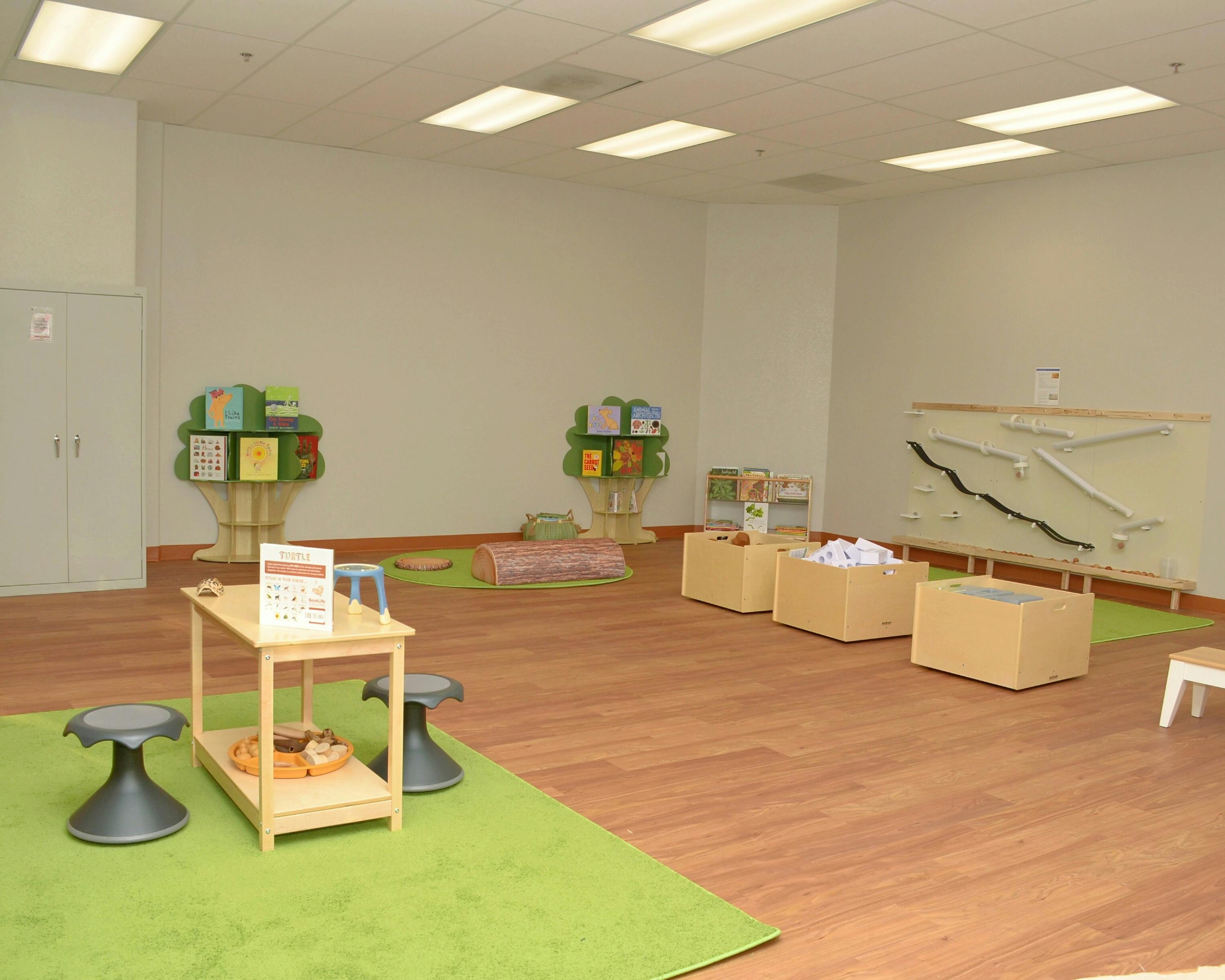 Empty classroom with small tables, stools, and play items