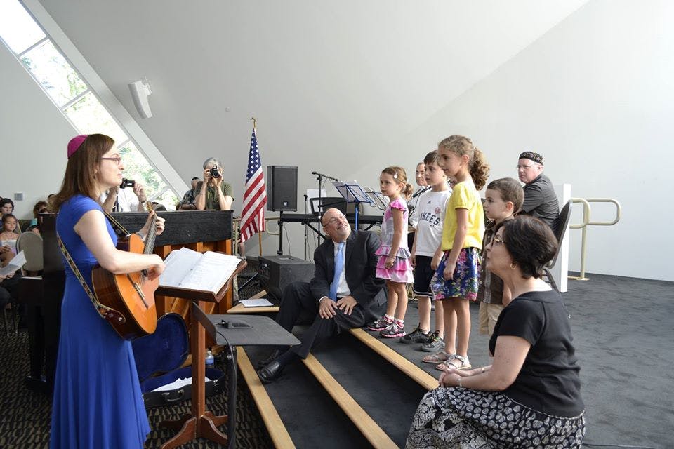 Person playing guitar for a group of children and adults