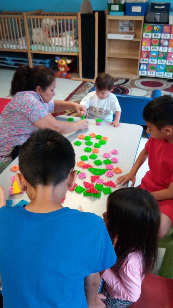 Adult and children playing with colorful interlocking toys at a table
