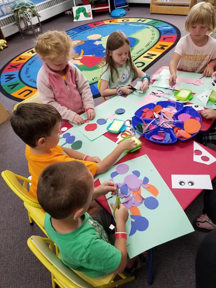 Children doing crafts at a table in a classroom