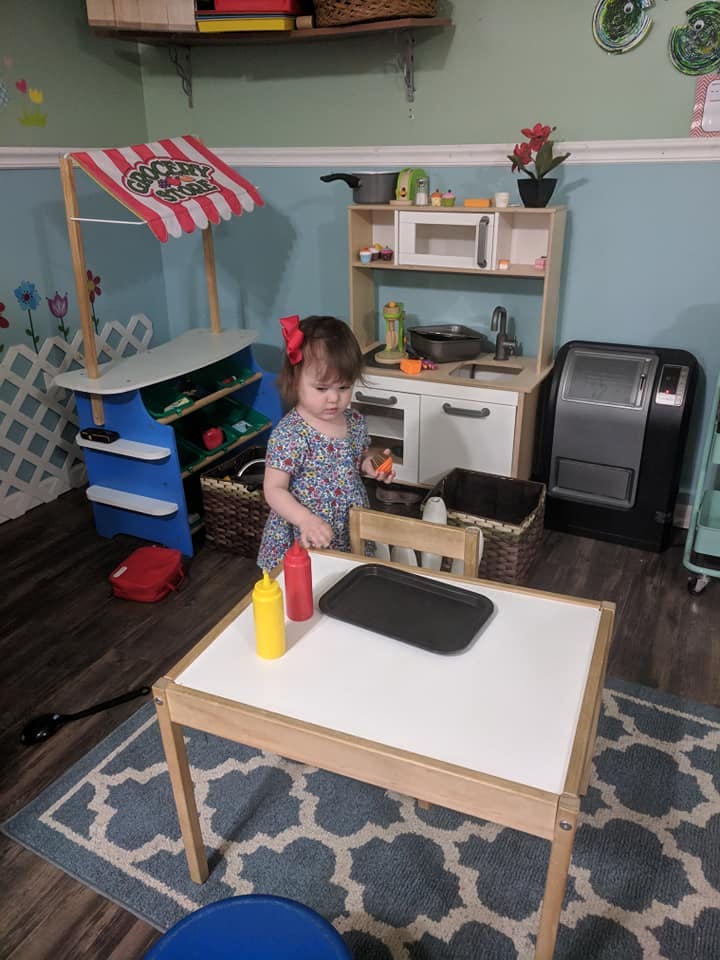 Child standing at a play kitchen set