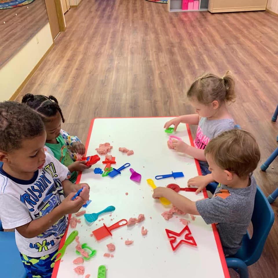 Children playing with modeling clay and tools at a table