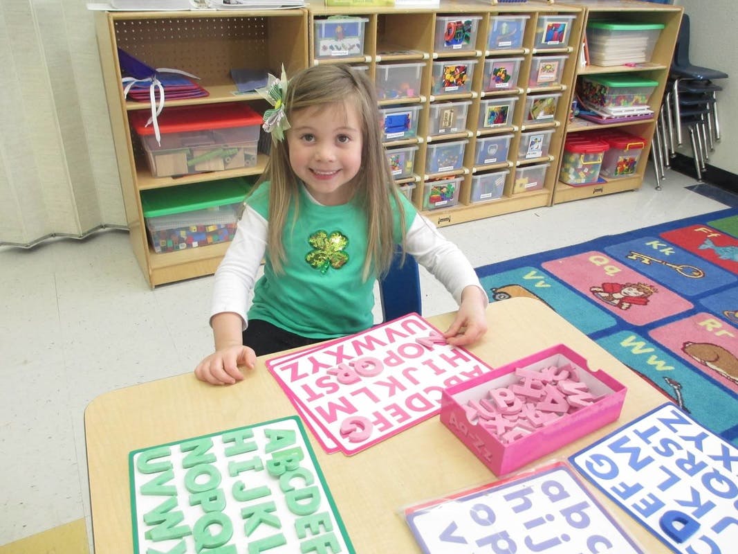 Child at a table with alphabet cards and letter cutouts