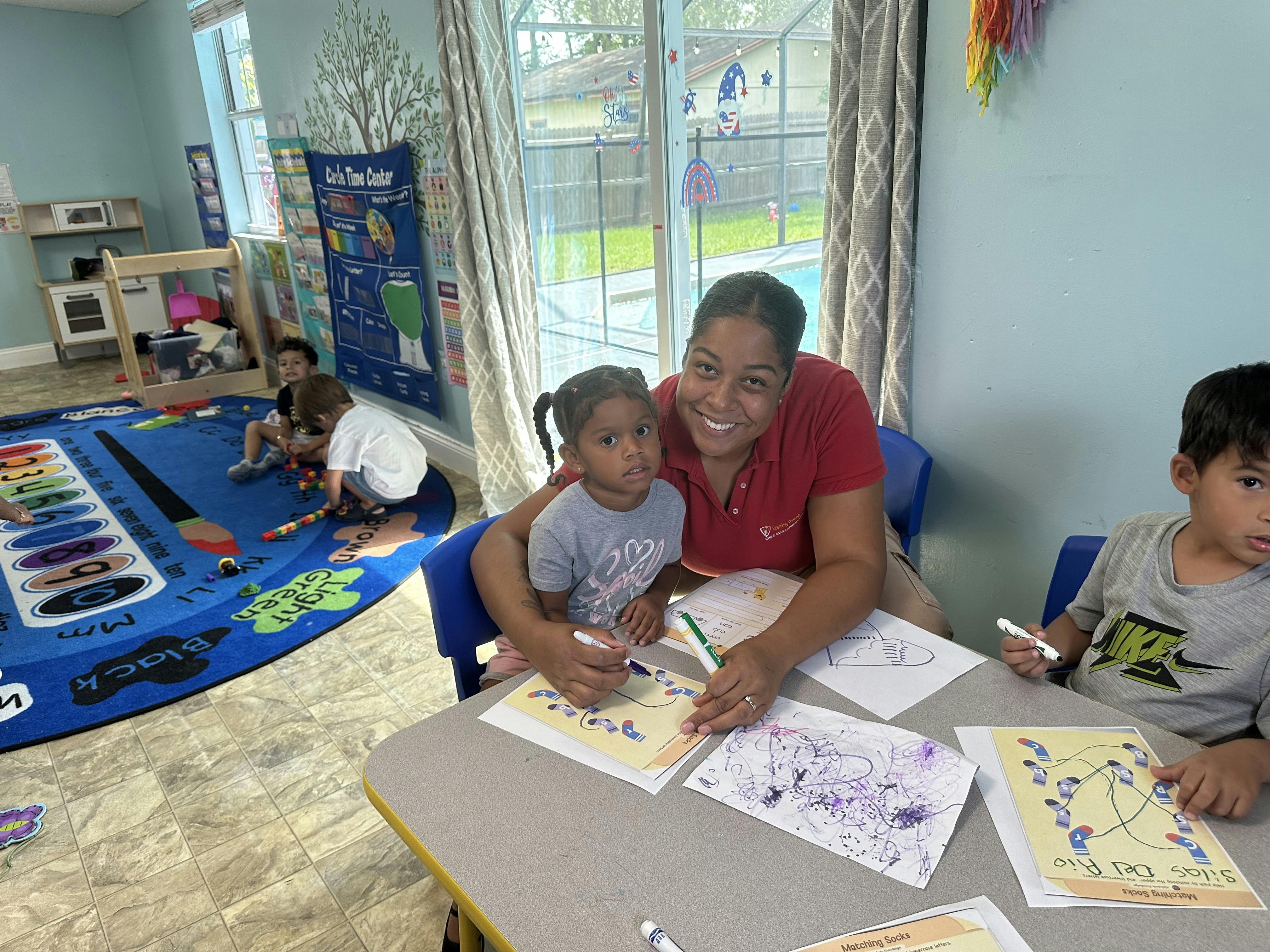 Adult and child drawing at a table in a classroom