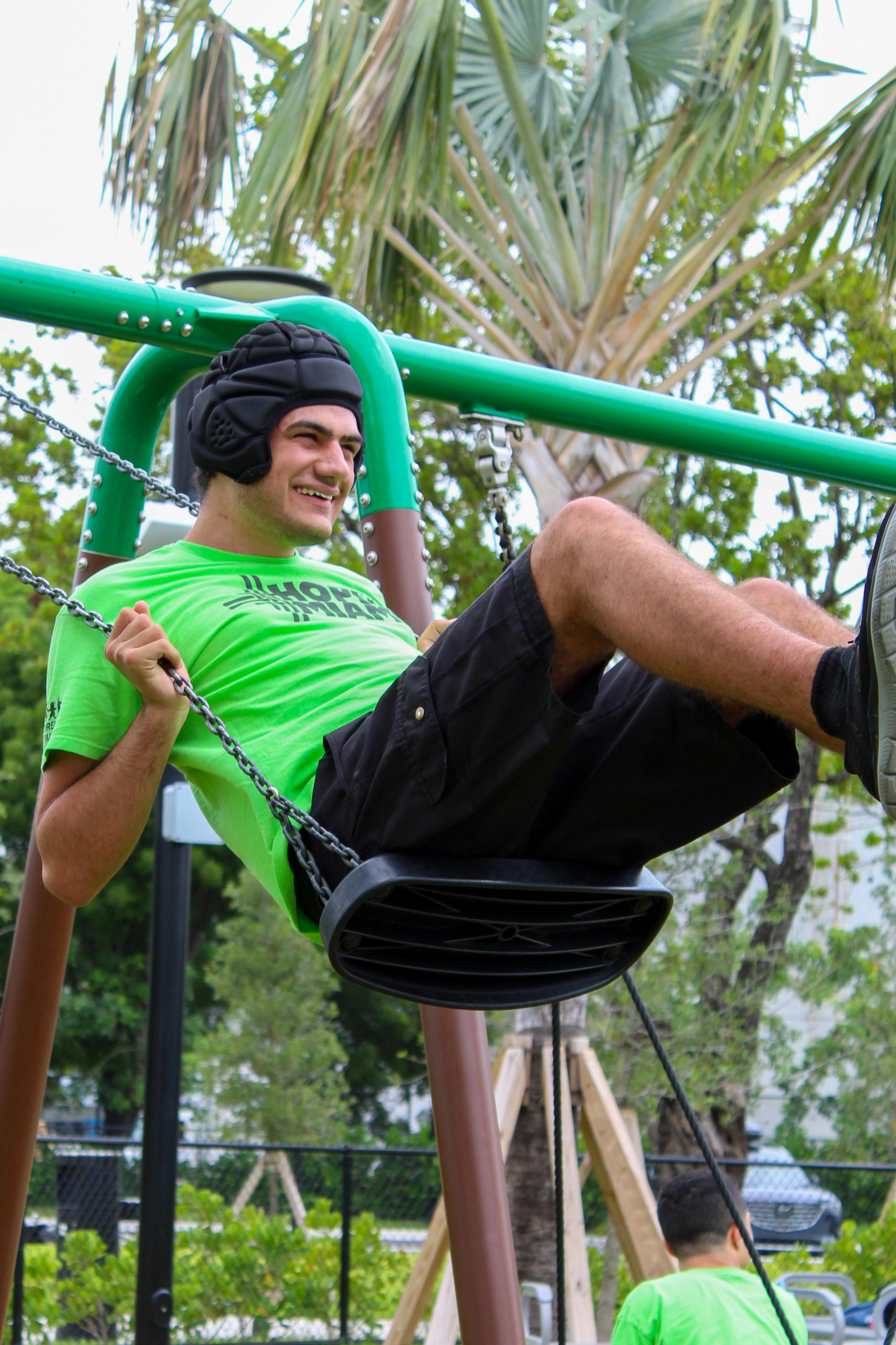Person wearing protective headgear sitting on a swing at a park
