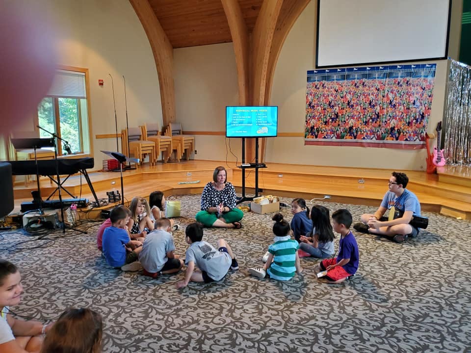 Adults and children sitting in a circle on a carpeted floor