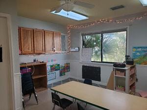 Classroom with a long table, chairs, cabinets, and a window
