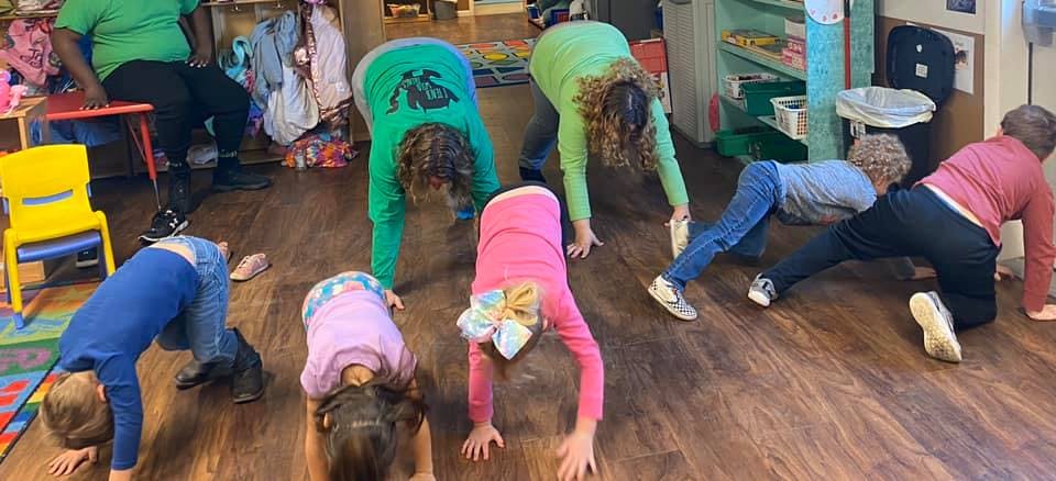Children and adults doing yoga poses on a wooden floor