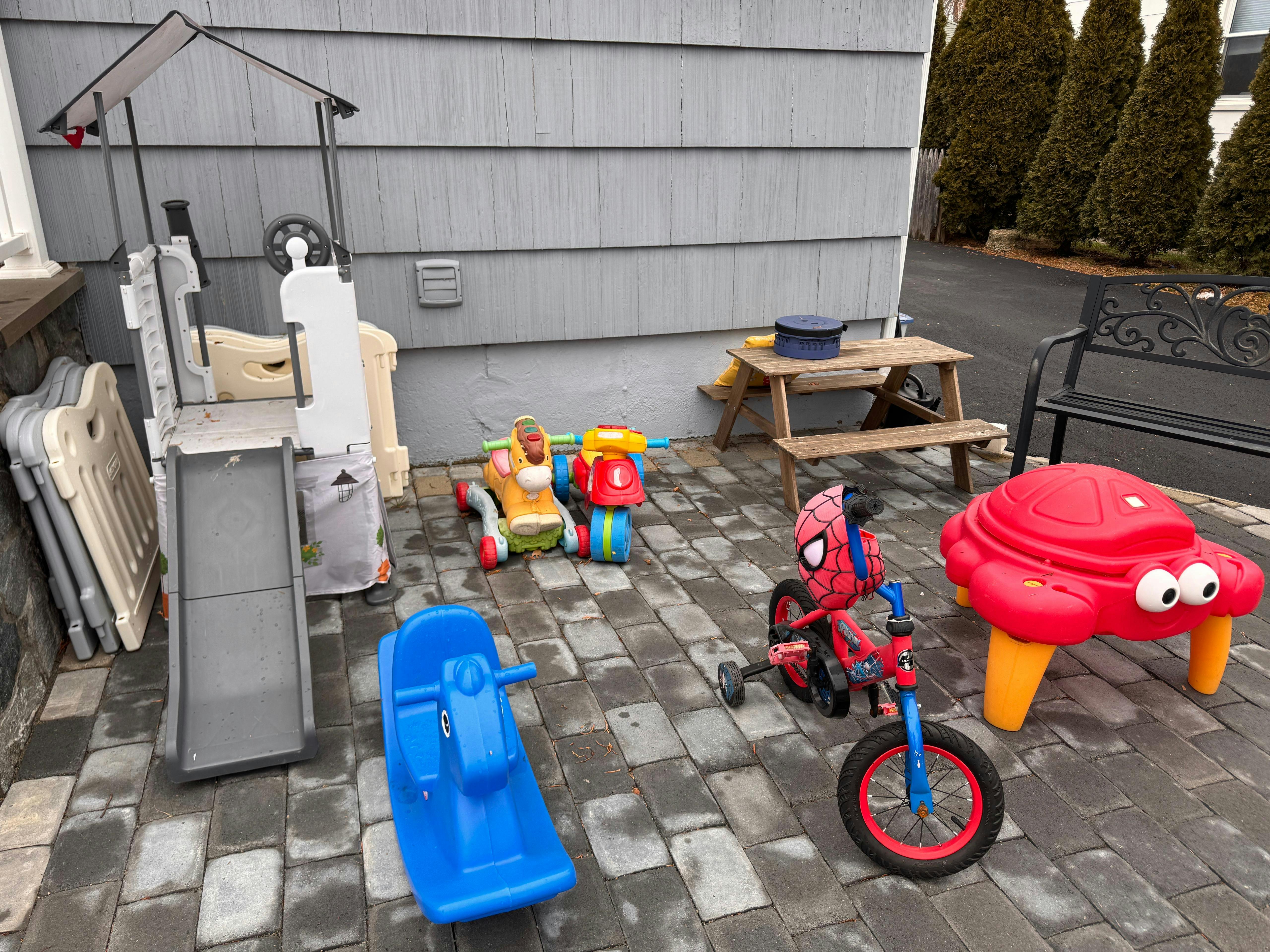 Children's outdoor play equipment including a slide, ride-on toys, and a picnic table
