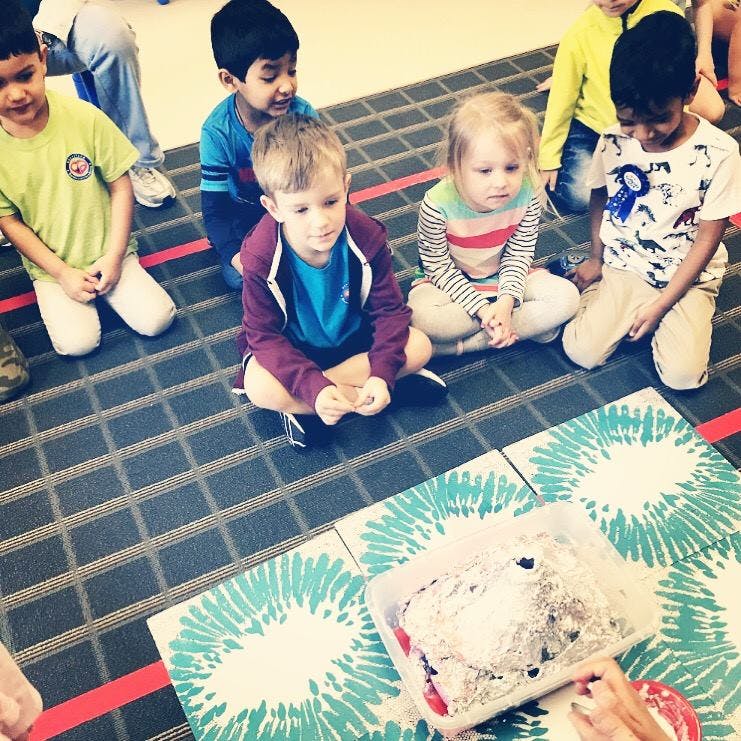 Children sitting on the floor looking at a container