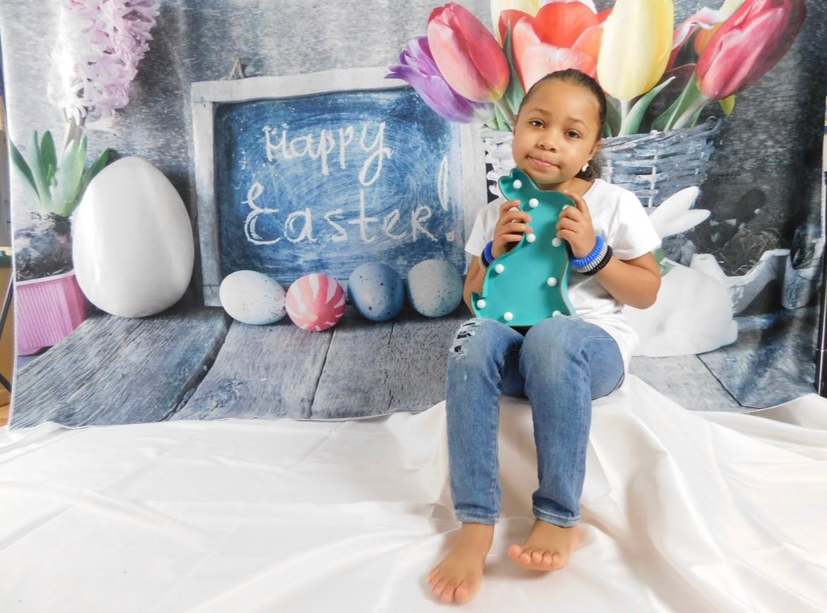 Child holding a bunny cutout in front of a Happy Easter sign