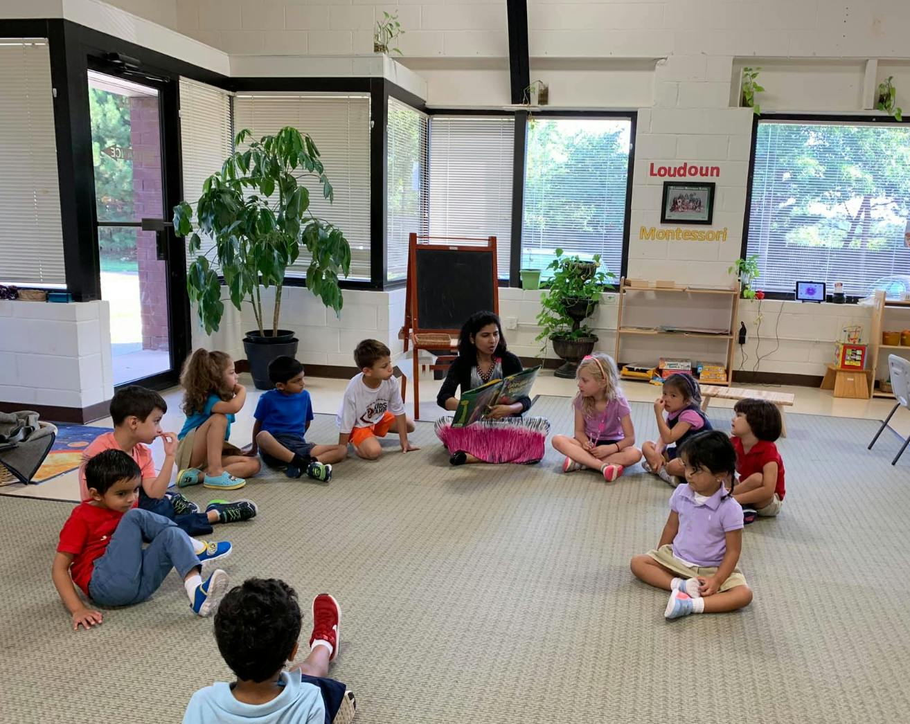 Person reading a book to a group of children in a classroom