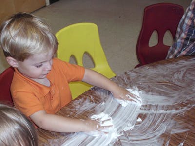 Child playing with white foam on a table