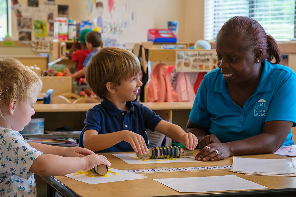 Adult and two children at a table in a classroom