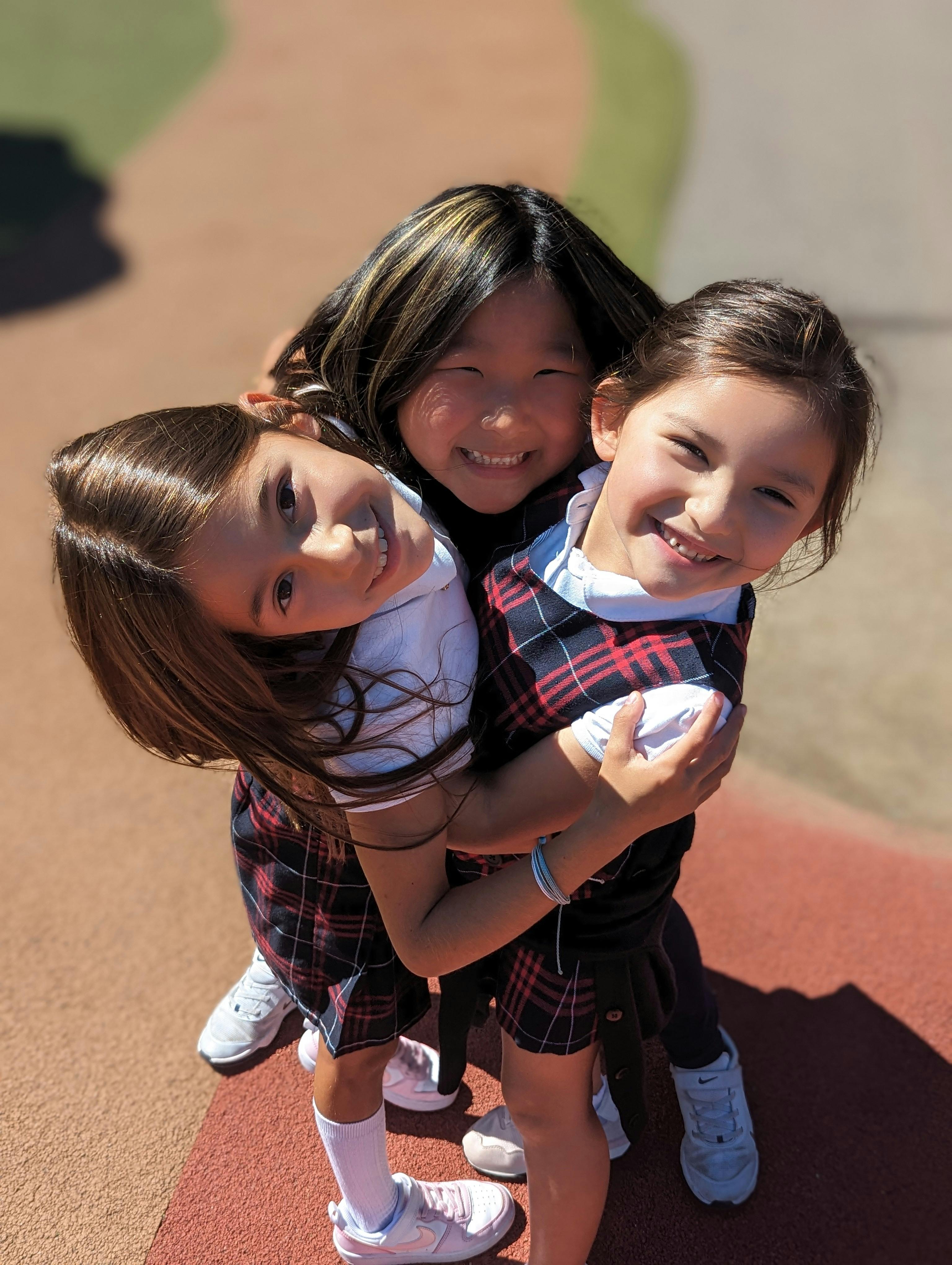 Three children in uniform hugging