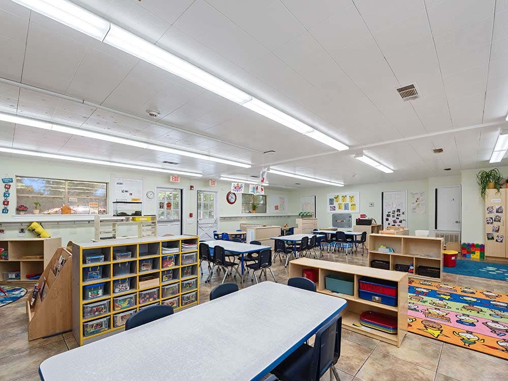 Empty preschool classroom with small tables and chairs