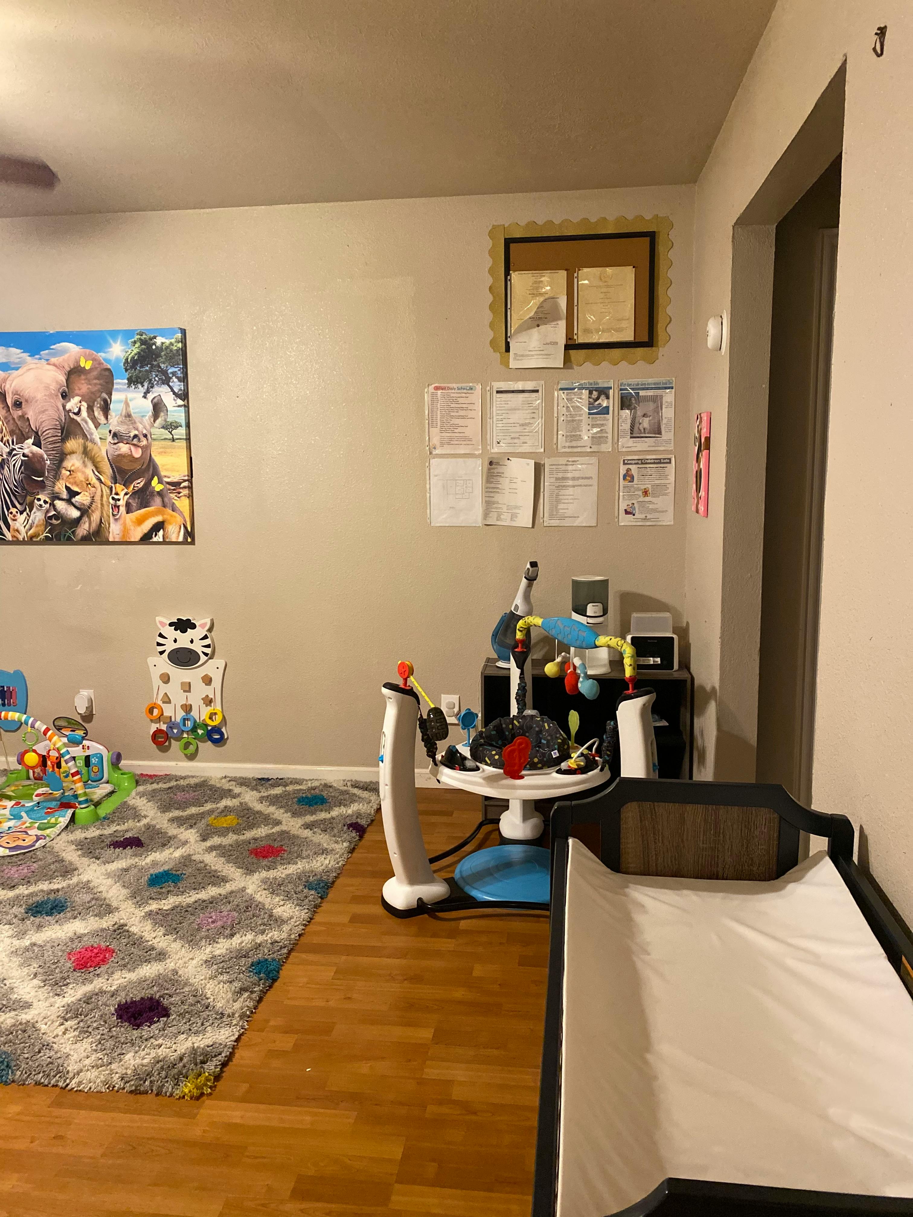 Playroom with a colorful rug, baby activity center, and animal-themed wall art