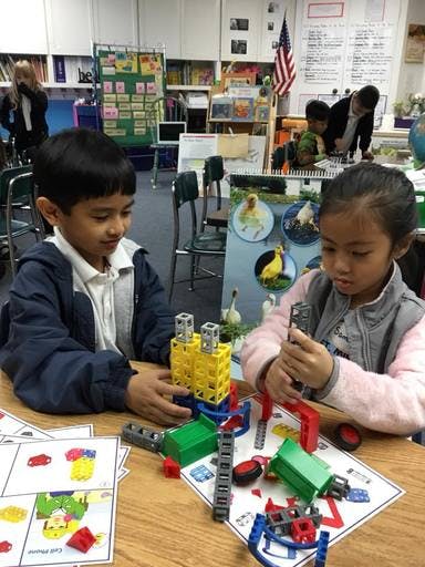 Two children building with construction toys at a table in a classroom