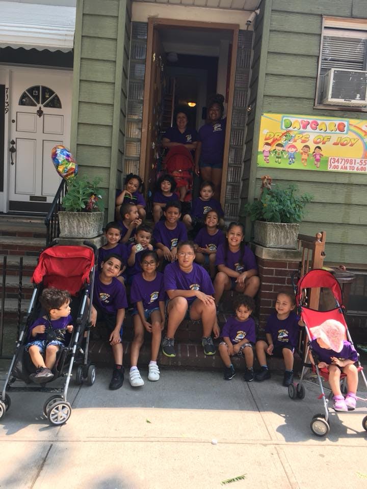 Group of children and adults in purple shirts on steps outside a building