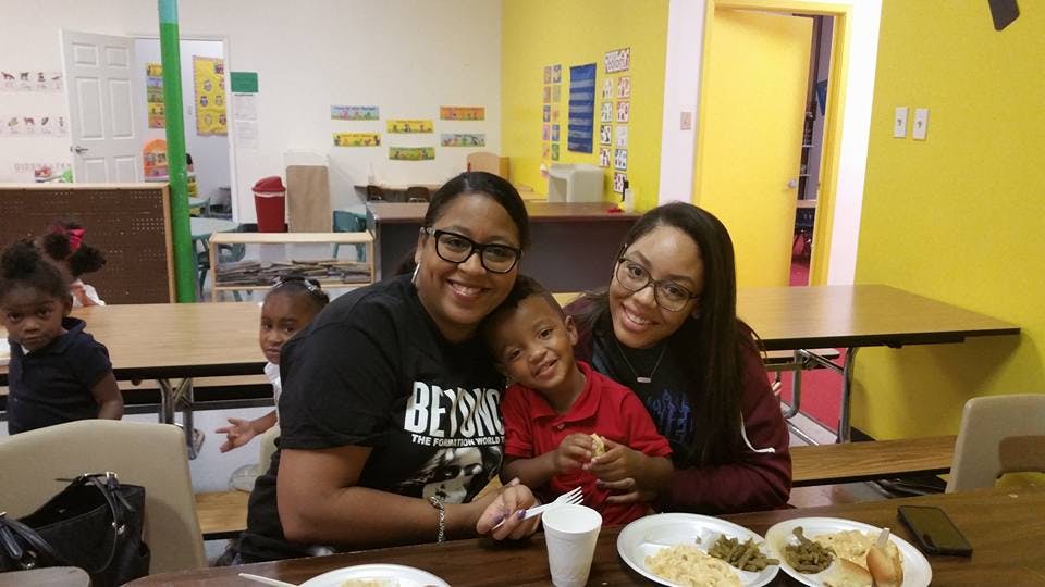 Two people and a child sitting at a table with plates of food