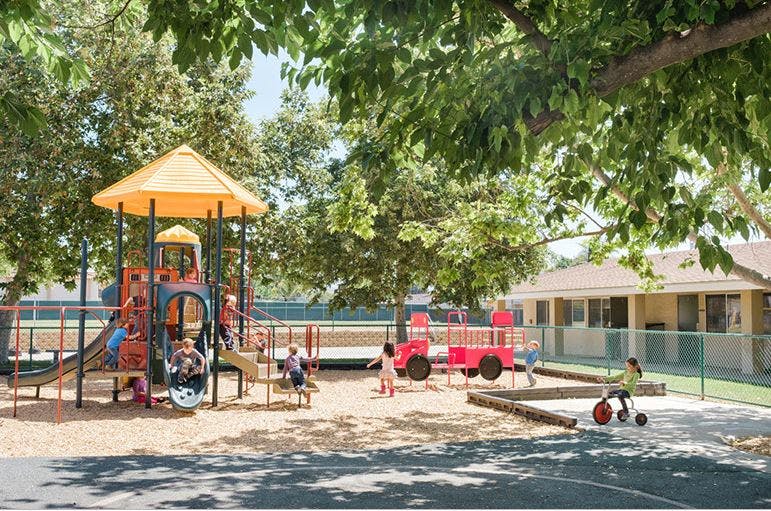 Children playing on a playground with slides, swings, and a toy truck