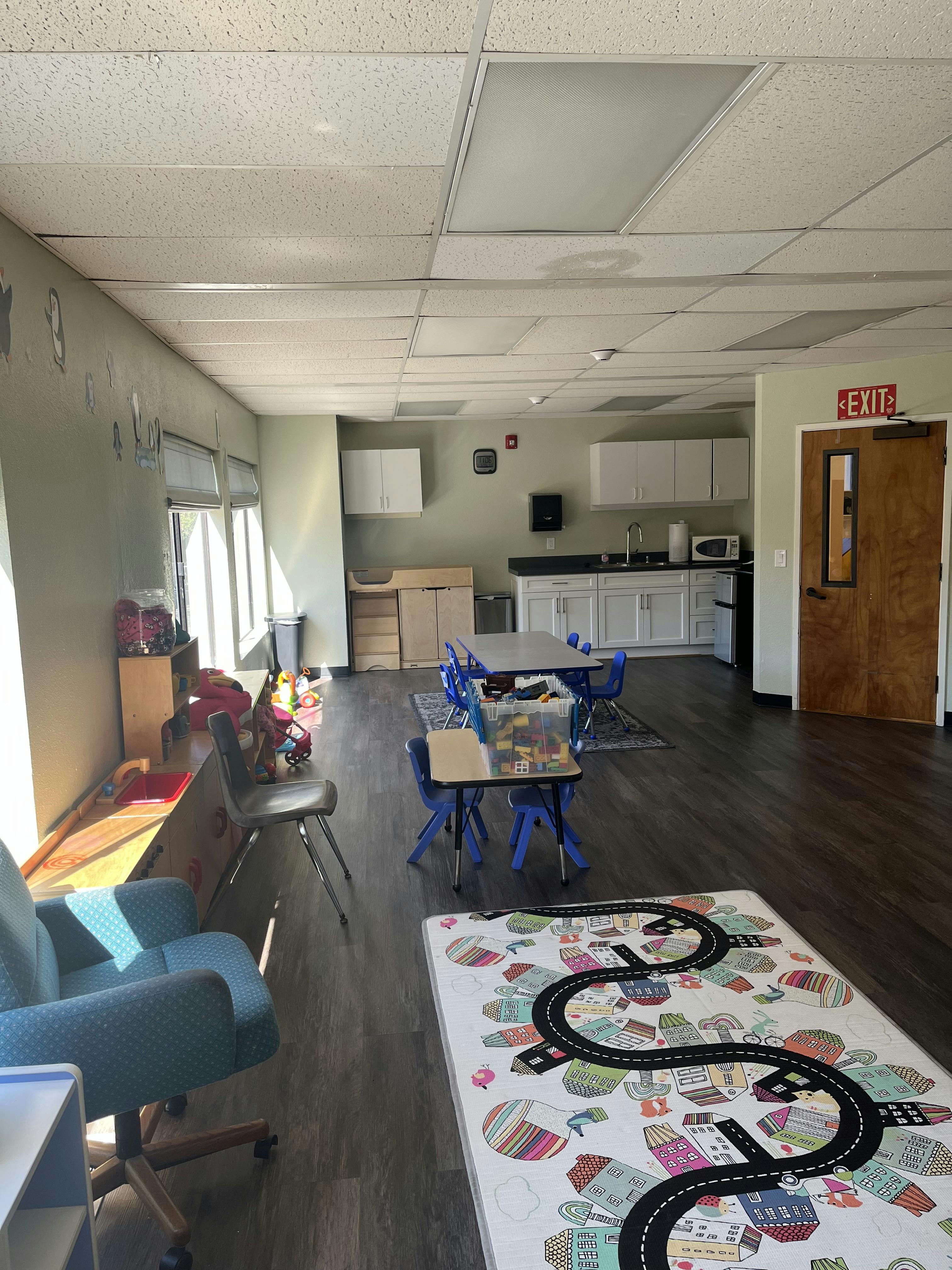 Childcare classroom with small tables and chairs and a road play mat