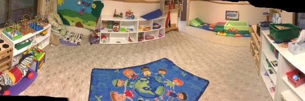 Playroom with shelves of toys, colorful rugs, and floor cushions
